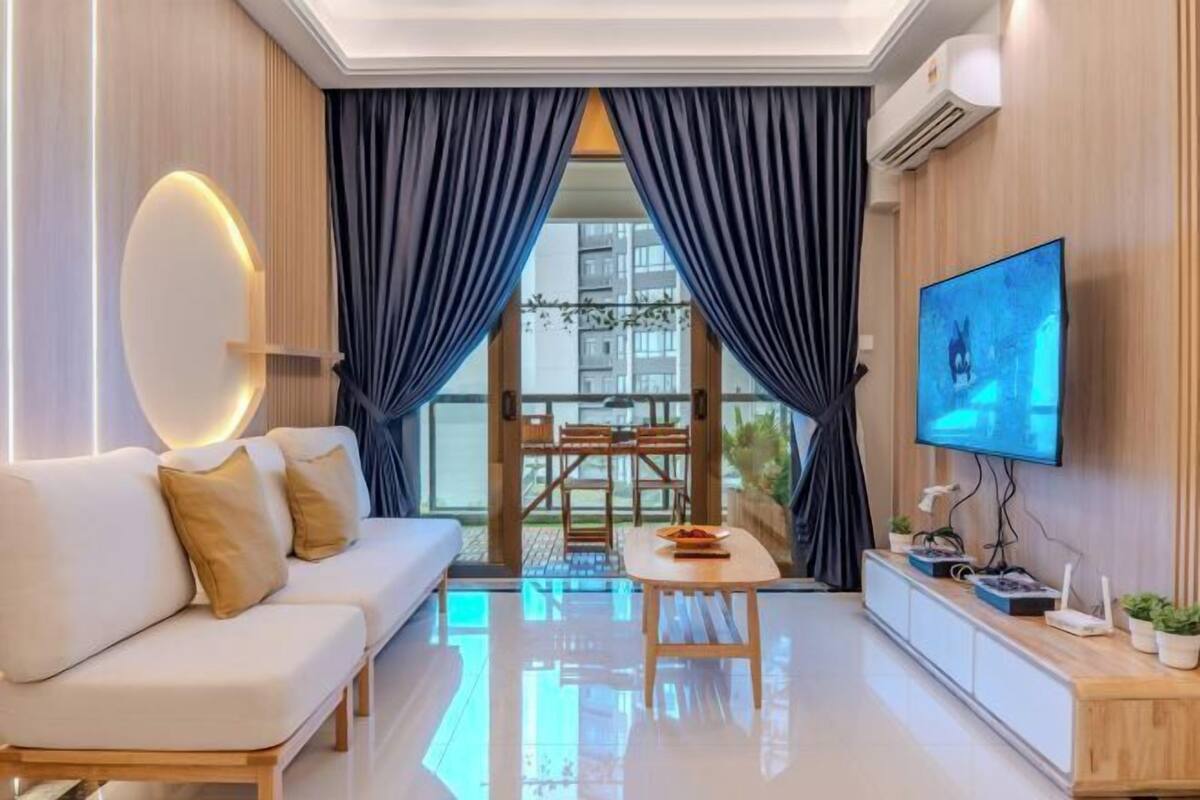 A modern living room with a sofa, a table, a TV, and a balcony view.