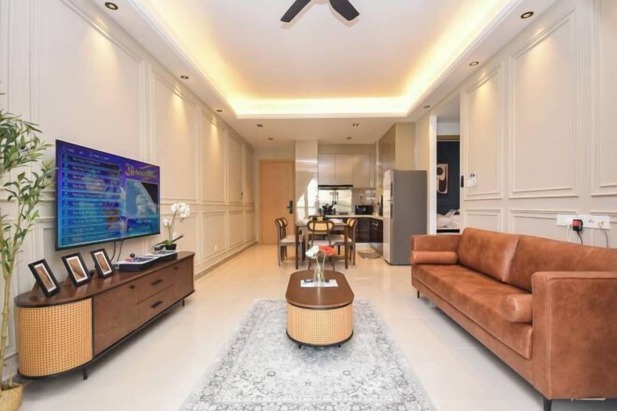 A living room with a TV, sofa, and a dining area in the background.