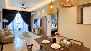 A modern hotel room with a dining area, a sofa, a TV, and a kitchen area. - R&F Princess Cove by Nest Home at Johor Bahru (Johor Bahru)