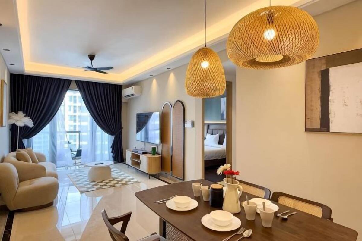 A modern hotel room with a dining area, a sofa, a TV, and a kitchen area.