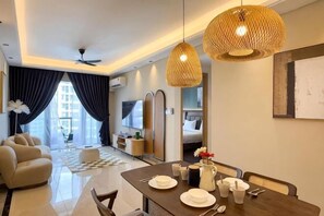 A modern hotel room with a dining area, a sofa, a TV, and a kitchen area. - R&F Princess Cove by Nest Home at Johor Bahru (Johor Bahru)