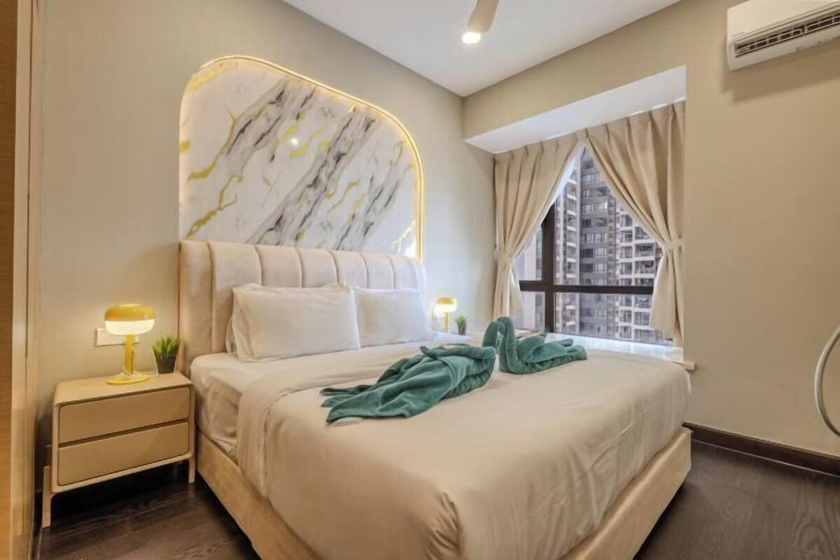 A modern bedroom with a marble headboard, a bedside table with a lamp, a bed with a green blanket, and a window with curtains.