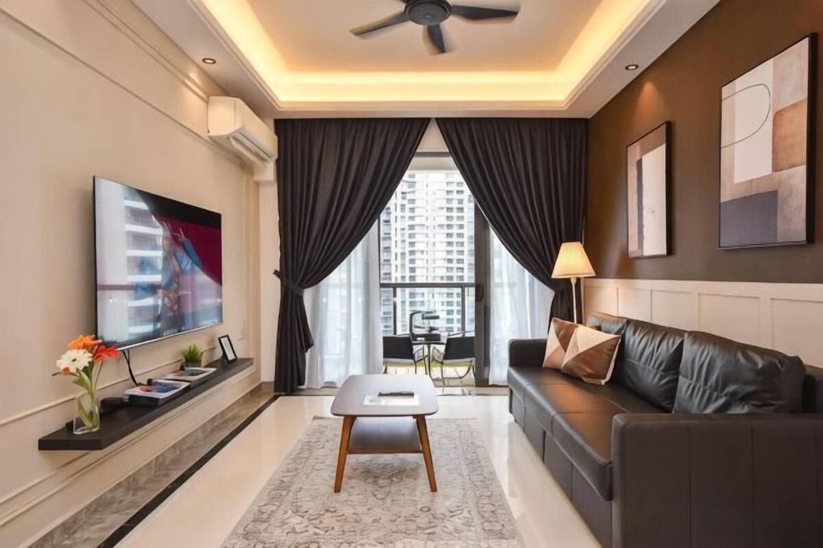 A modern living room with a flat-screen TV, a sofa, a coffee table, and a ceiling fan.