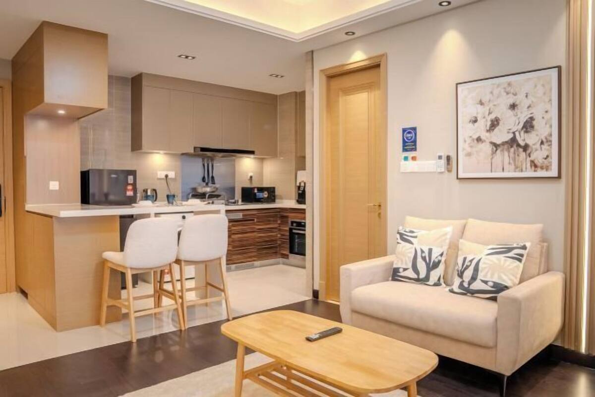 A modern living room with a sofa, a coffee table, and a kitchen area with a dining table and chairs.