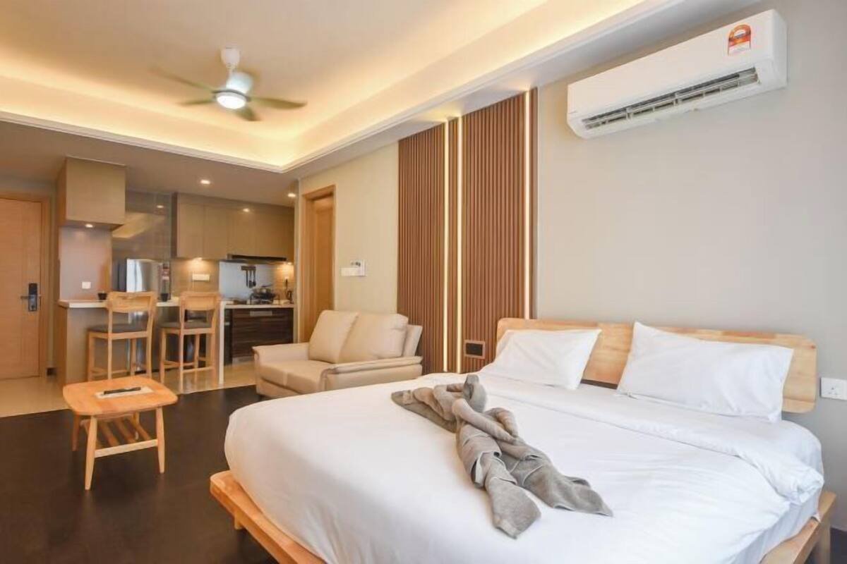 A hotel room with a bed, a desk, a chair, and a kitchenette.