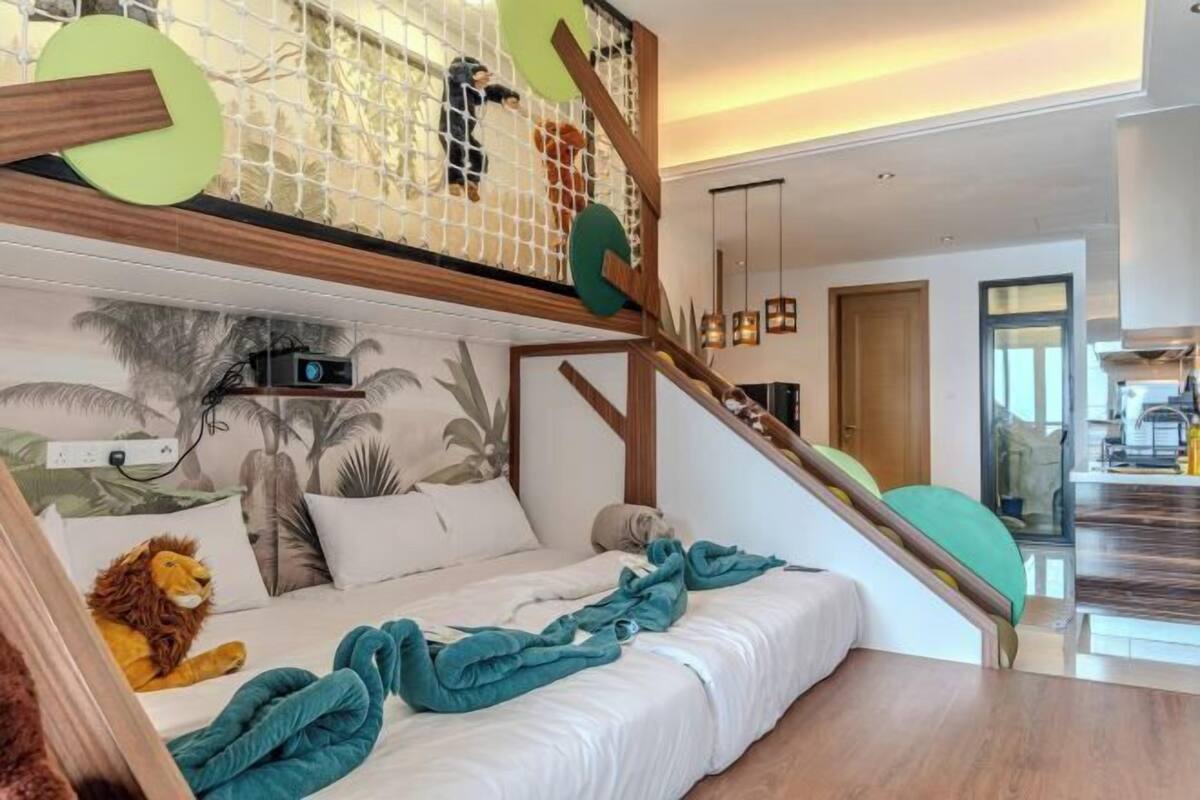 A bedroom with a bed, a staircase, a mural, and a kitchen area.