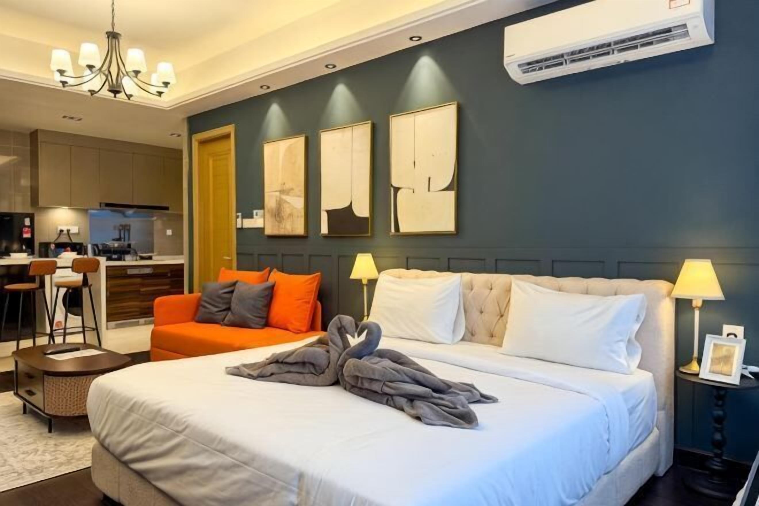 Habitación de hotel con cama, escritorio, sillón, sofá y obras de arte en la pared.