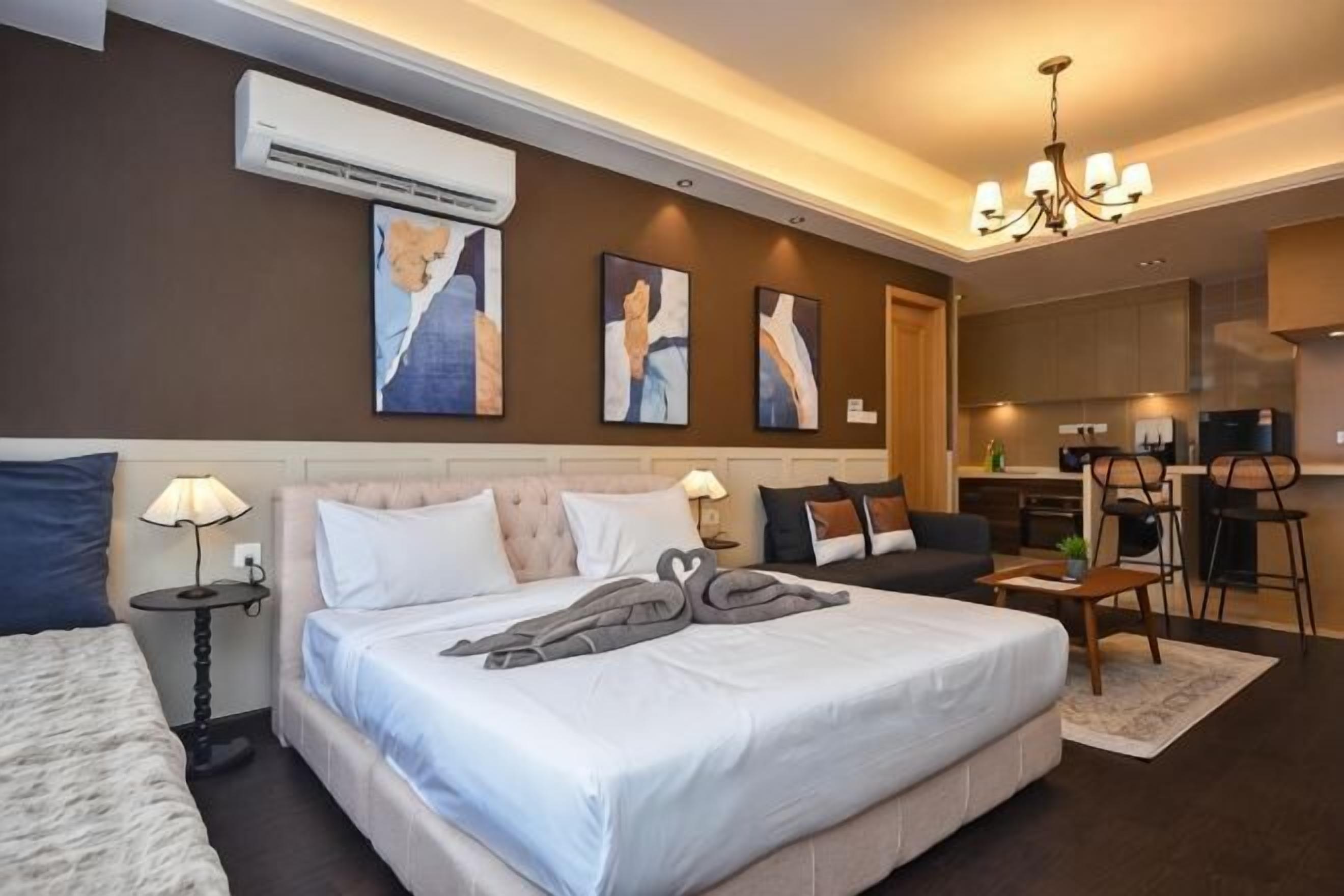 Una habitación de hotel con una cama grande, un escritorio, una silla, una mesita y un equipo de aire acondicionado en la pared.