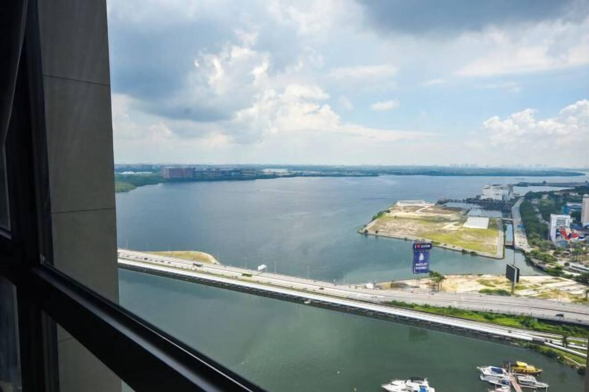 A view of a river with a bridge, boats, and buildings across the water.