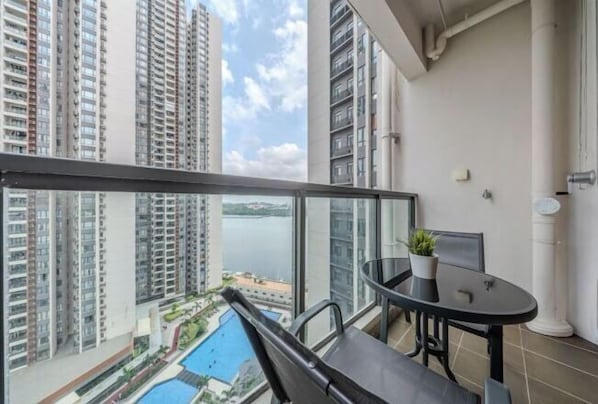 A balcony with a view of high-rise buildings and a body of water.