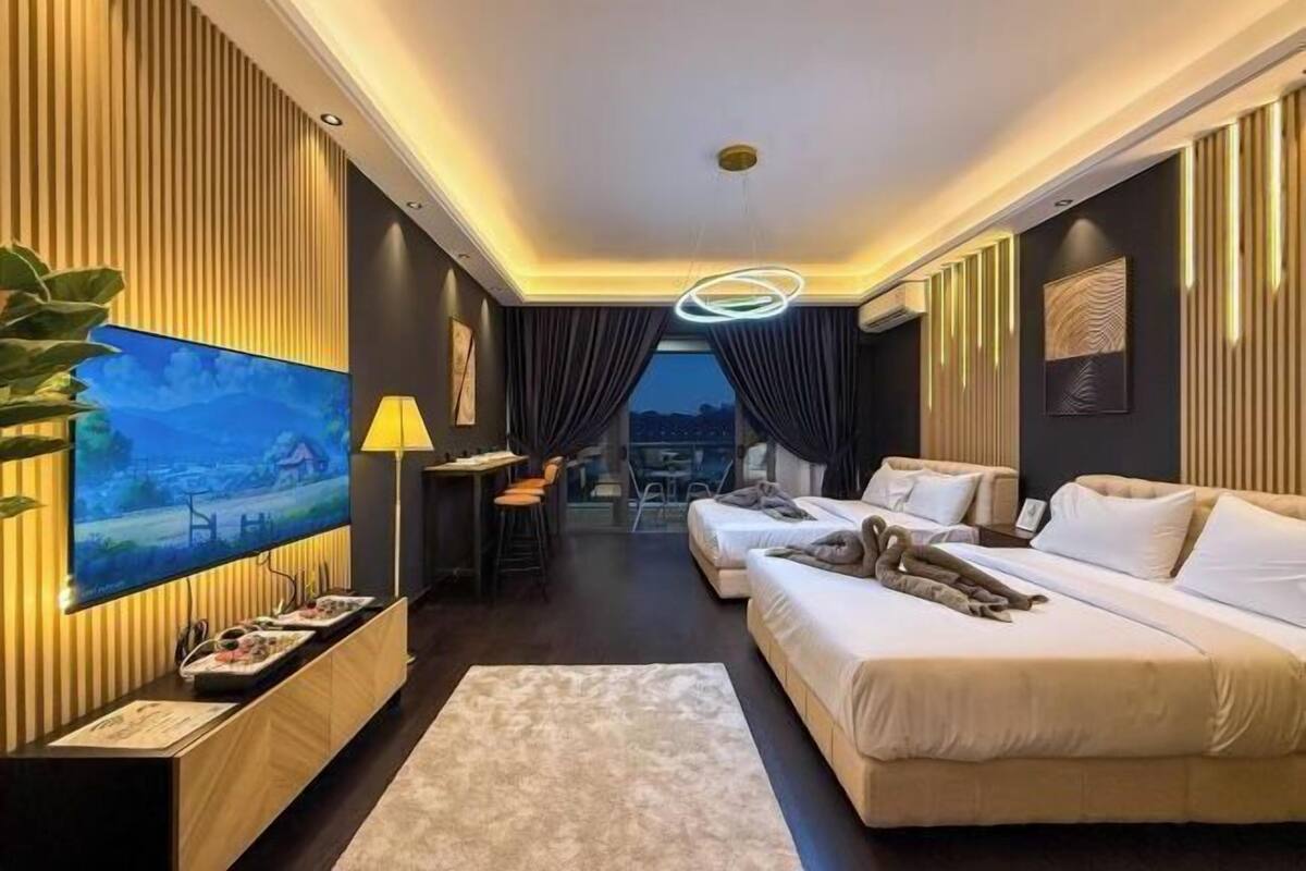 A modern hotel room with a TV, two beds, a dining area, and a view of the city.