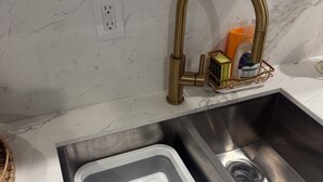 A kitchen sink with a modern faucet, a built-in trash bin, and a soap dispenser.