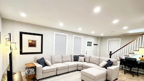 A modern living room with a sectional sofa, a coffee table, a TV, and a patterned rug. - Renovated 3-bedroom house in Montgomery VT, close to Jay Peak (Montgomery Center)