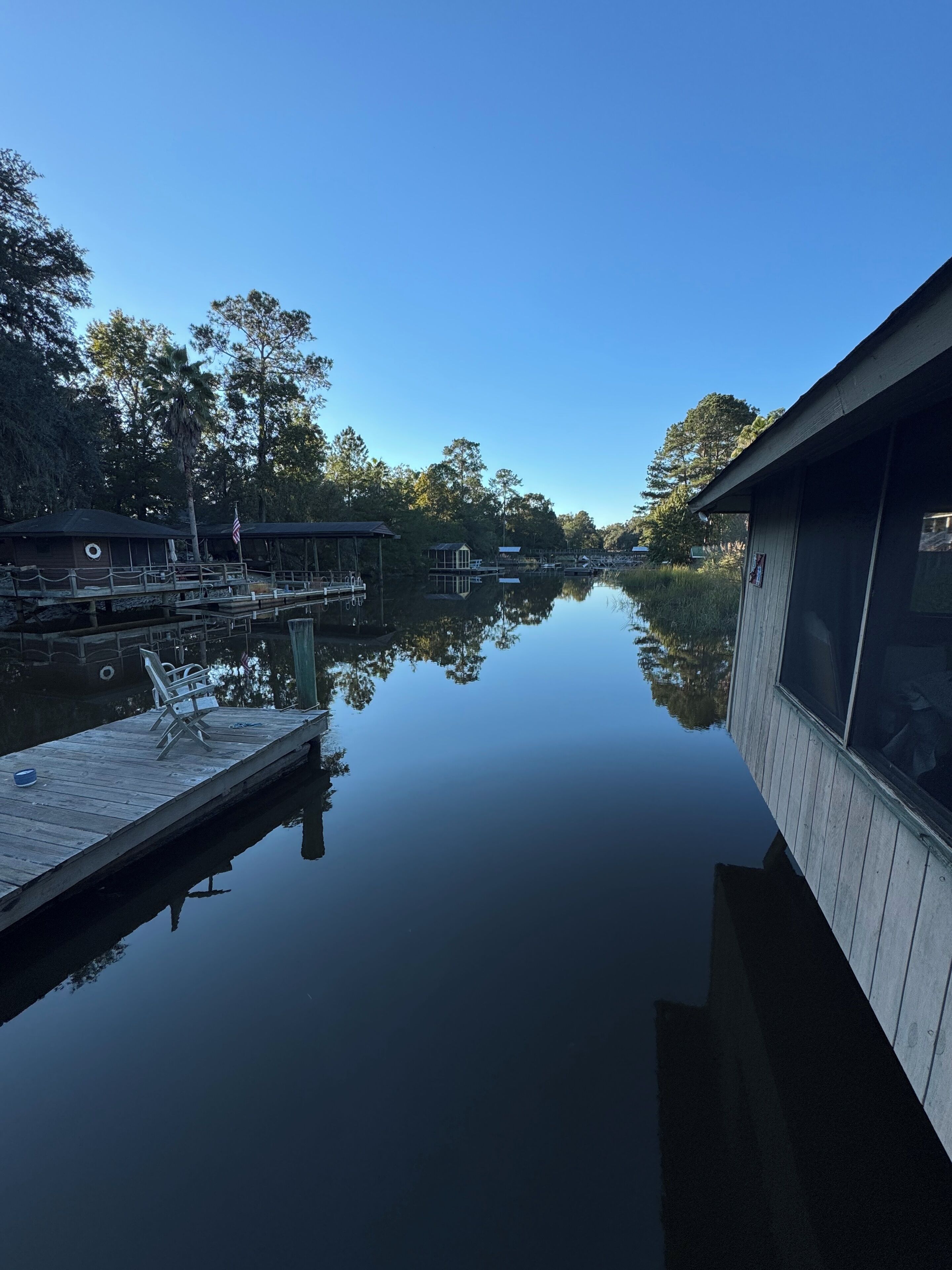 A calm lake with a wooden dock and a small cabin.