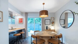 Ein moderner Essbereich mit einem runden Holztisch, sechs Stühlen und einer hängenden Pendelleuchte.