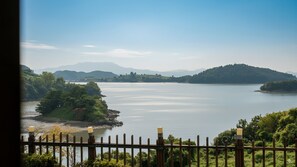 A view of a lake with surrounding hills and a wooden fence in the foreground. - Yeosu Greenhouse Pension (Yeosu)