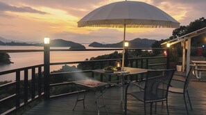 An outdoor dining area with a table and chairs, overlooking a body of water and hills. - Yeosu Greenhouse Pension (Yeosu)