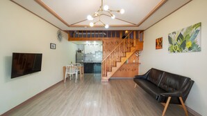 Un vaste salon agrémenté d’un escalier en bois, d’un coin repas et d’une cuisine située au fond de la pièce.