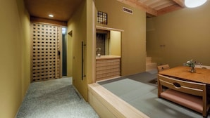 Een traditionele Japanse kamer met tatami vloeren, een houten tafel met een vaas en een schuifdeur met een lattenwerkpatroon.