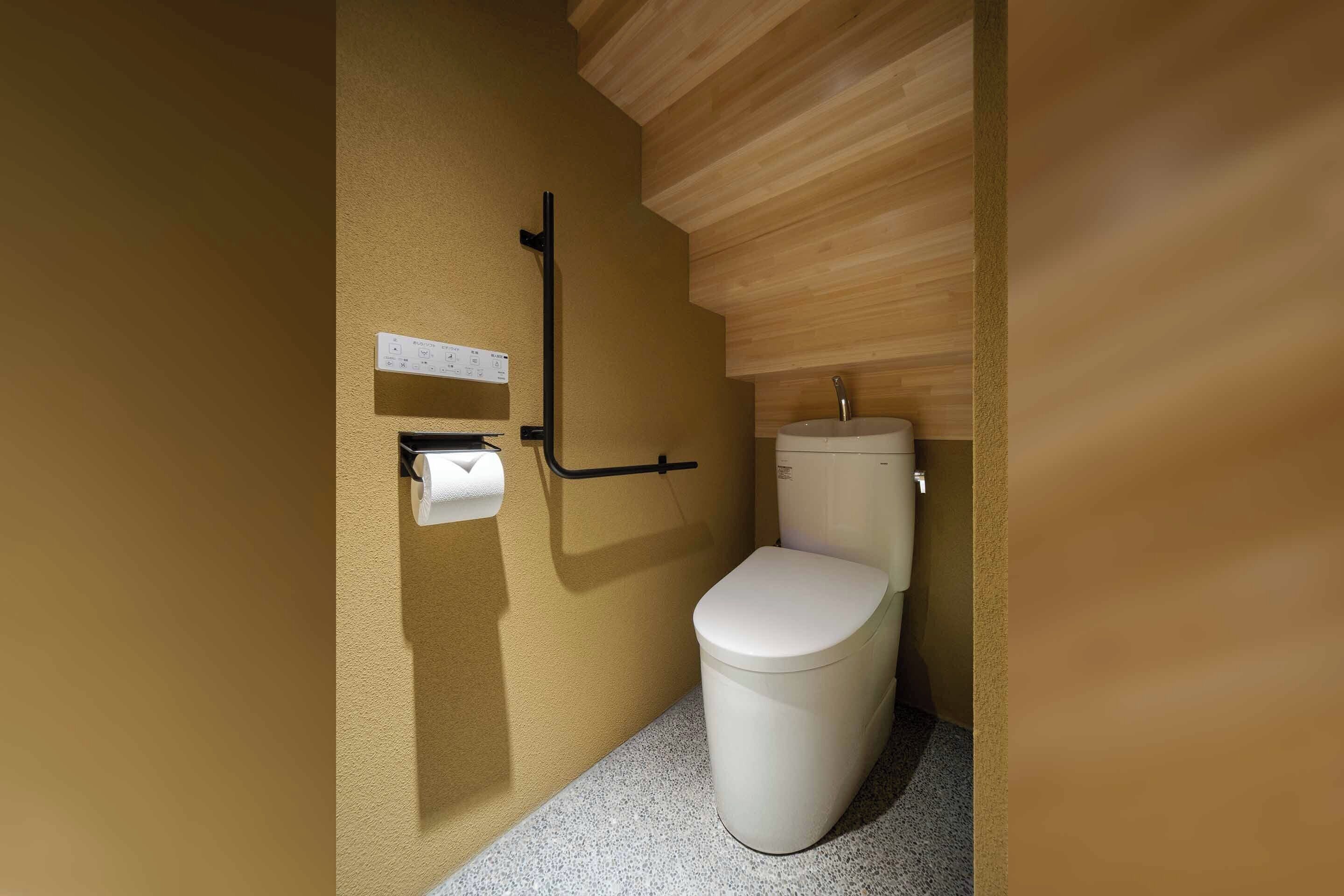 Ein modernes Badezimmer mit Toilette, Handtuchspender und Haltegriff.