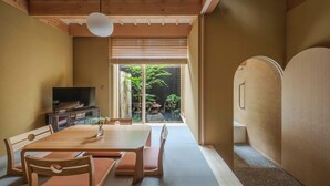 Een traditionele Japanse kamer met tatami vloeren, een lage houten tafel en een televisie op een kast.