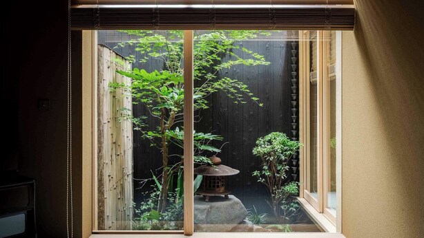 Een traditionele Japanse kamer met tatami vloerbedekking, een shoji schuifdeur en uitzicht op een Zen-tuin met een lantaarn.