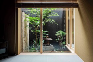 Ein traditioneller japanischer Raum mit Tatami-Boden, einer Shoji-Schiebetür und Blick auf einen Zen-Garten mit einer Laterne.