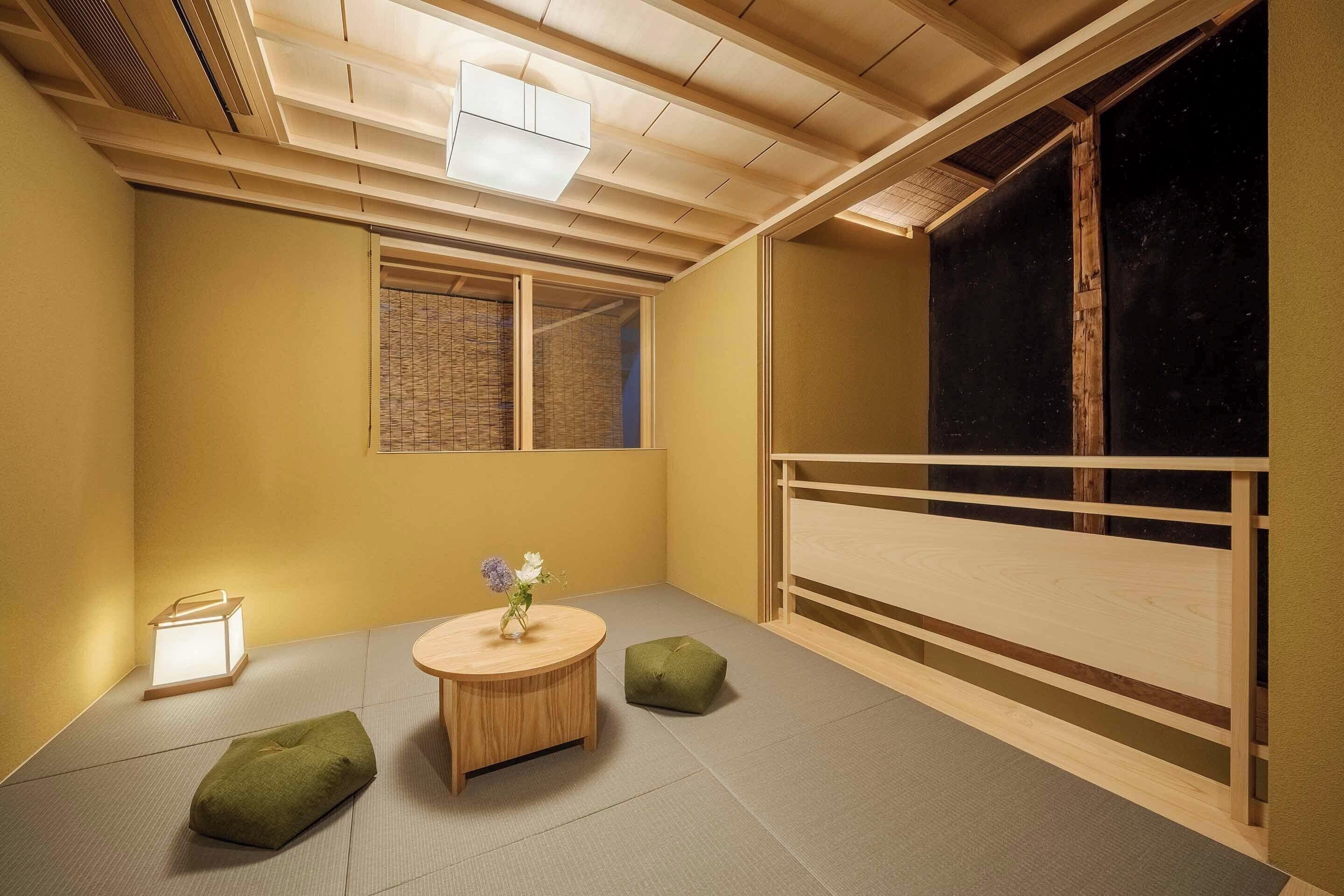Una tradizionale stanza giapponese con pavimento in tatami, un tavolo in tatami, un piccolo sgabello, una lanterna e una porta scorrevole.