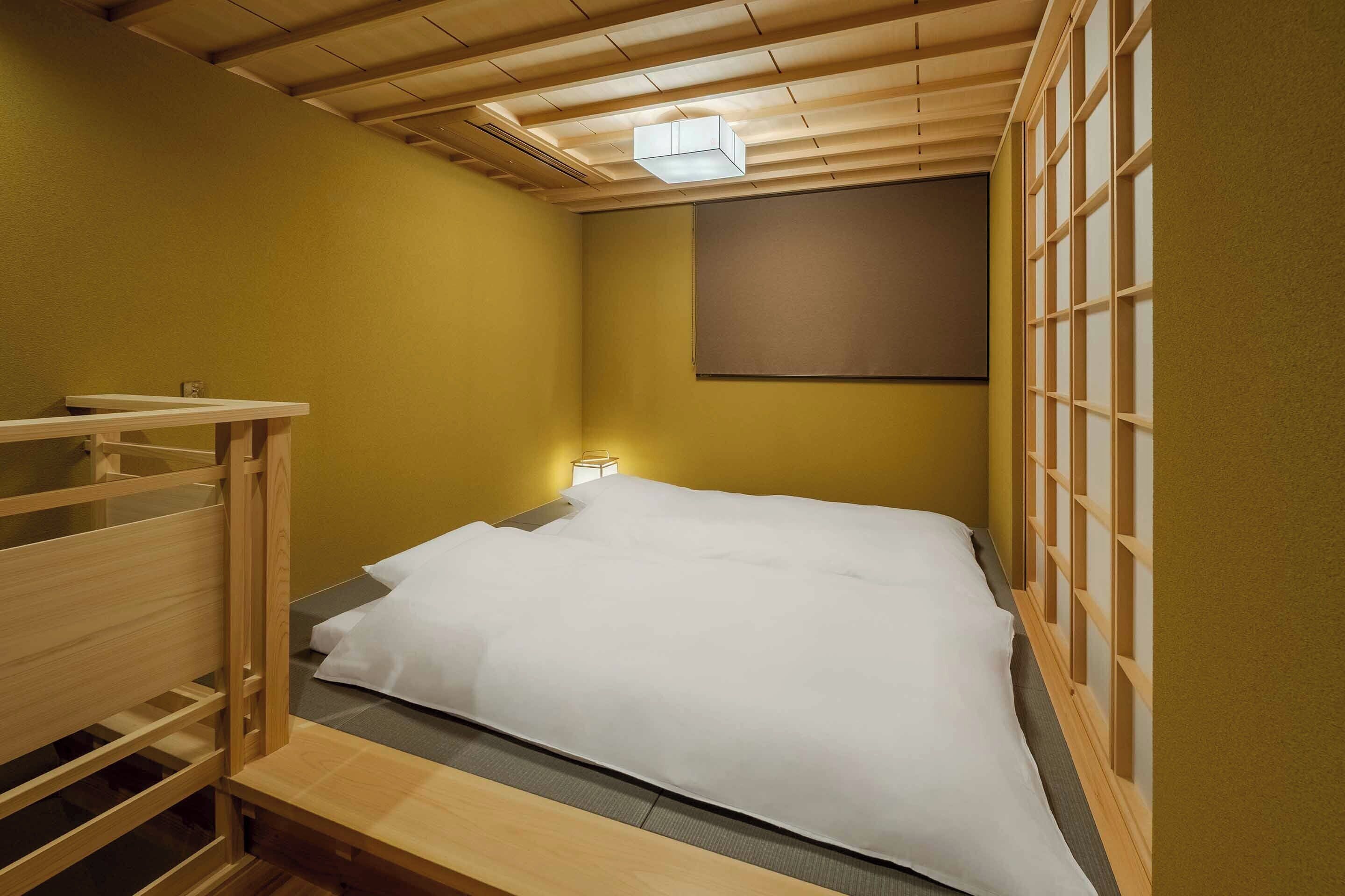 A single bed with a wooden headboard and footboard, a bedside table, and a wall-mounted light.