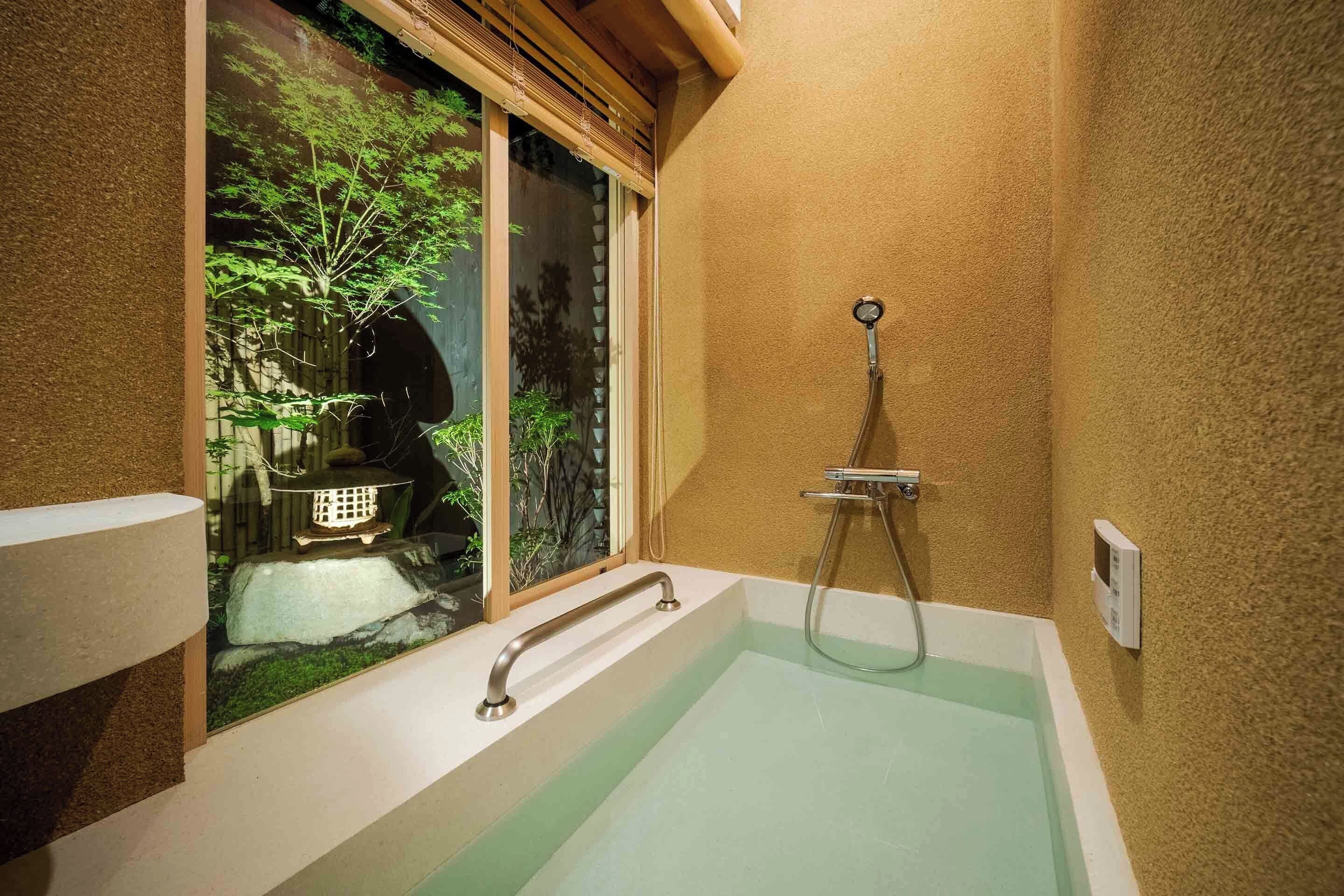Un baño con bañera, ducha y ventana con vistas a zonas verdes.