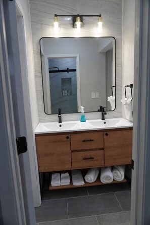 Une salle de bain avec un double lavabo, un miroir et un porte-serviettes.