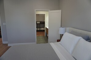 Une chambre à coucher comprenant un lit, une table de chevet et une porte donnant sur une salle de bain.