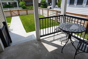 Une terrasse couverte avec une table et des chaises, une clôture en bois et une pelouse.