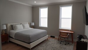 Une chambre à coucher avec un lit, deux lampes de chevet, un bureau et une chaise.