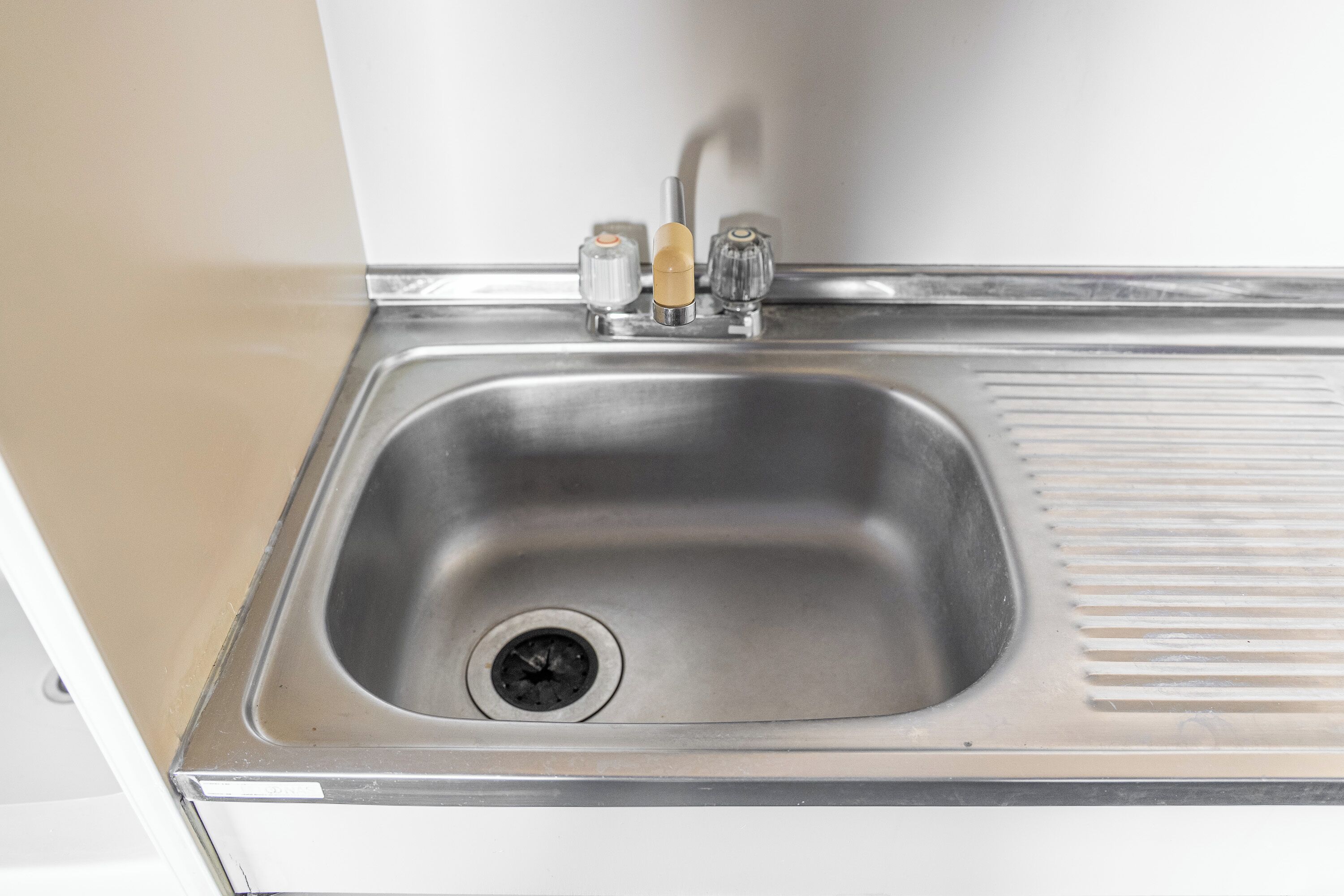 A stainless steel sink with a single faucet and a drain.