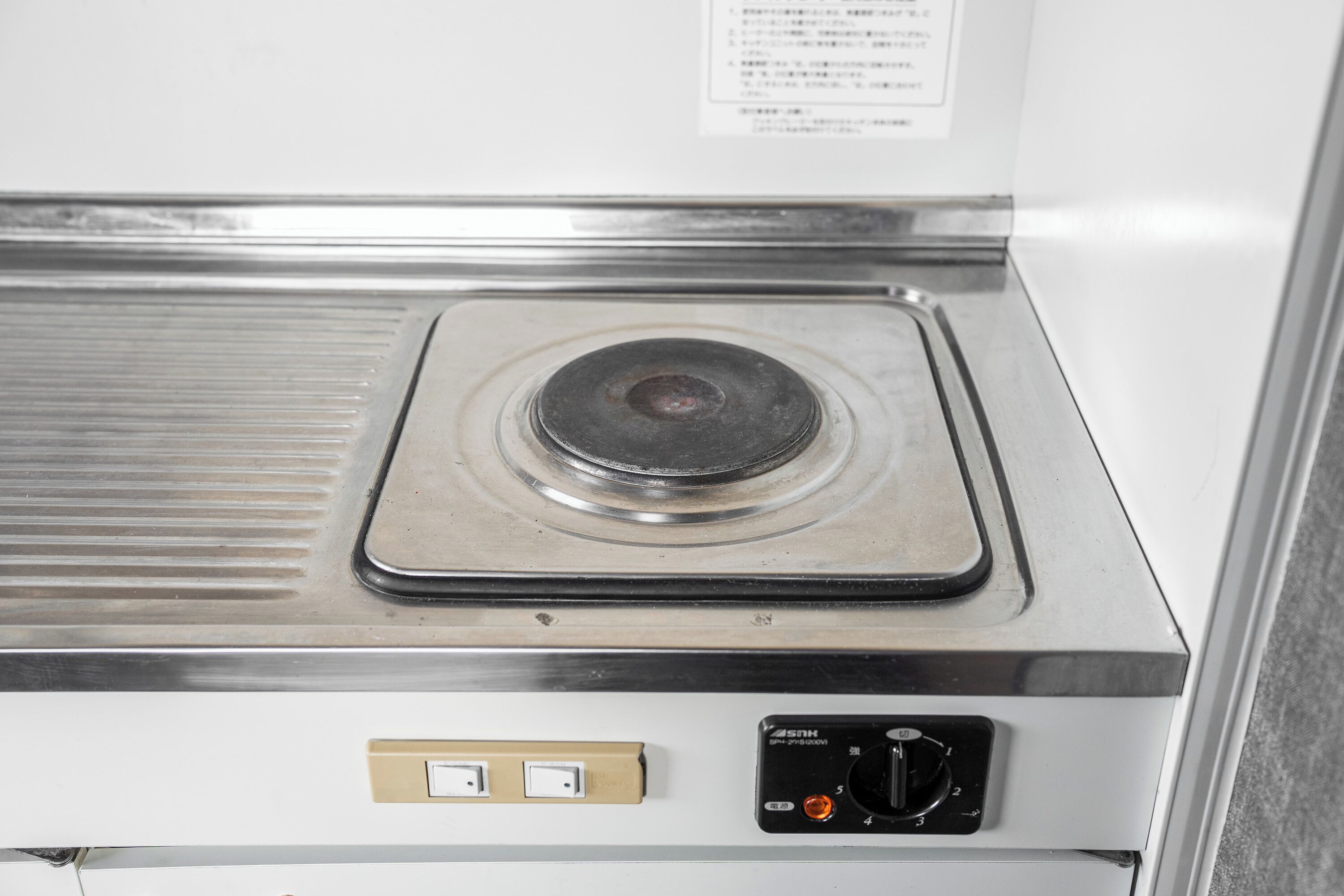 A kitchen with a gas stove, two electrical outlets, and a control panel.
