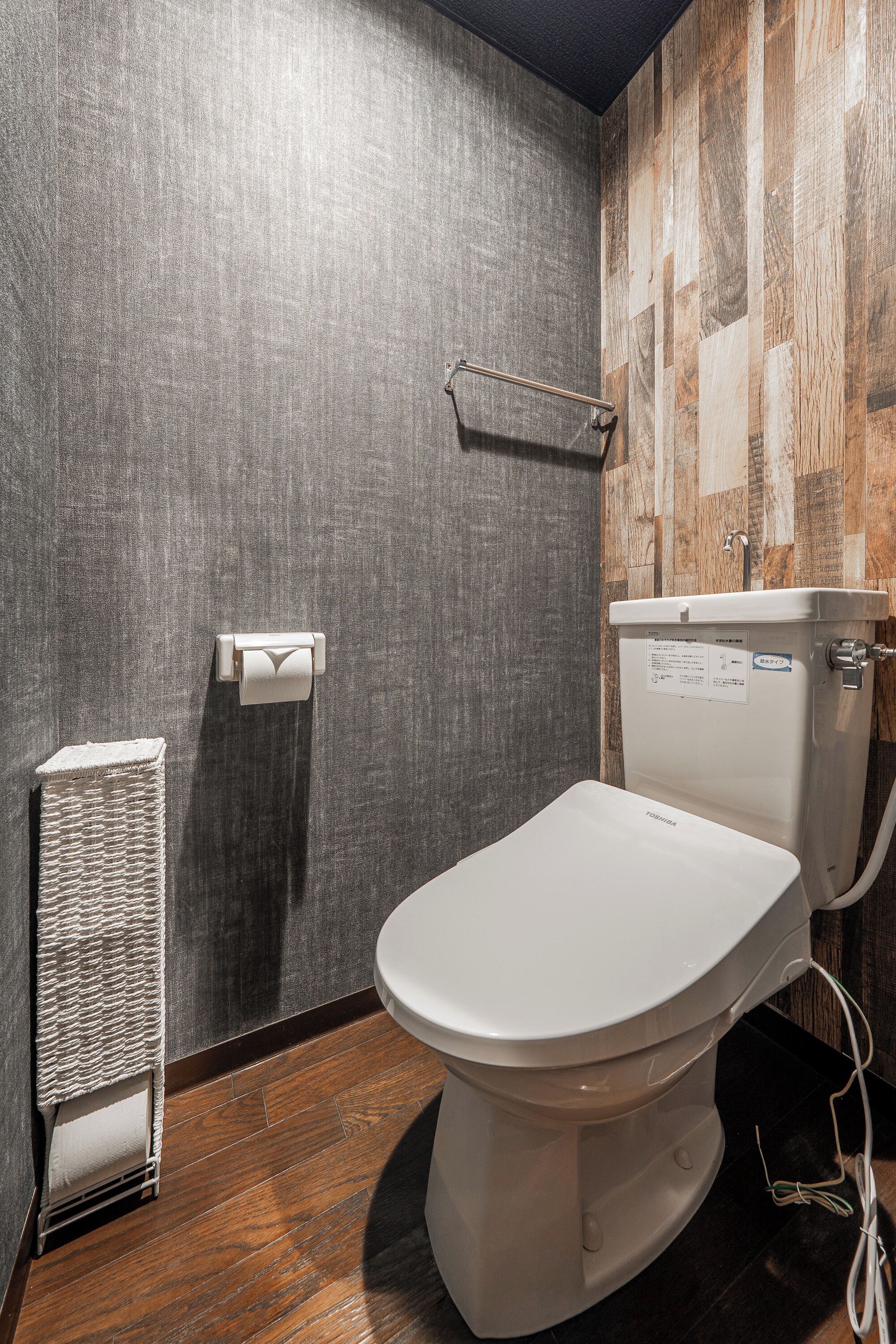 A modern bathroom with a toilet, a towel warmer, and a wooden wall.