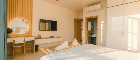 A modern hotel room with a bed, a desk, a chair, a mirror, and a wardrobe.