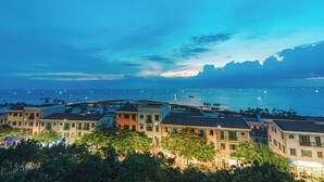 A coastal town at dusk with buildings overlooking the sea, boats, and a clear sky. - Rosy Hotel (Phu Quoc)