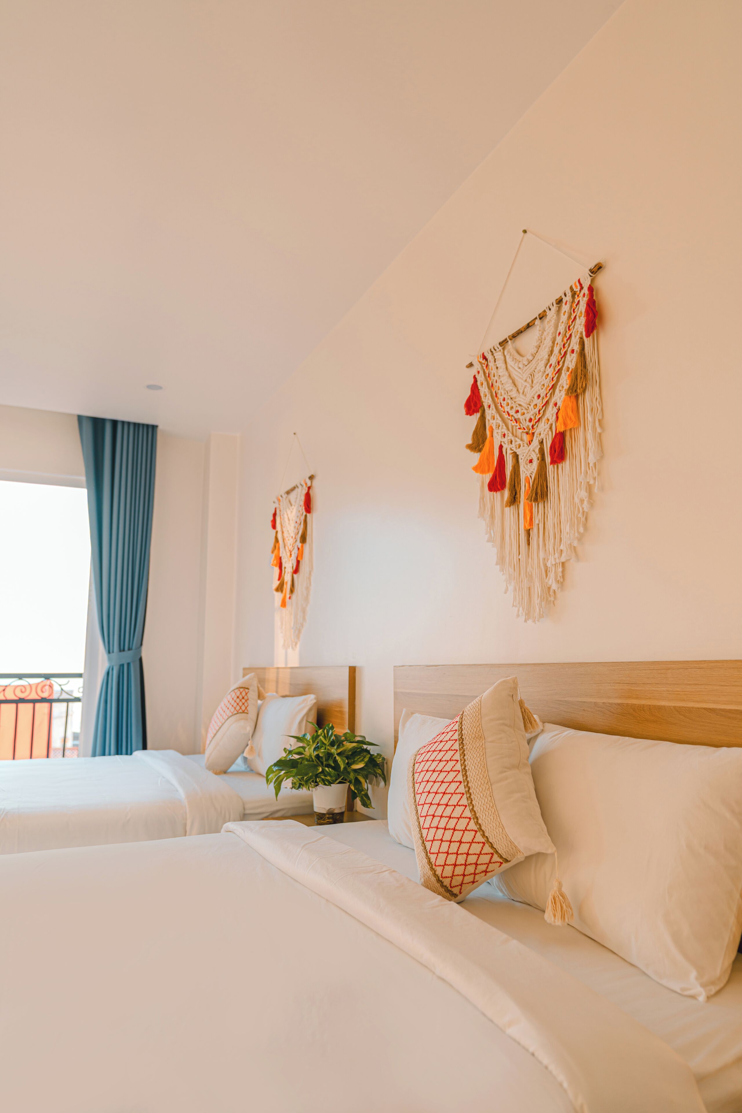 Une chambre d’hôtel avec deux lits, une plante en pot et des éléments de décoration murale.