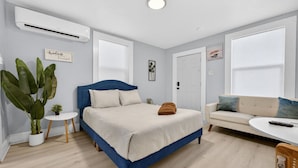Ein Schlafzimmer mit einem Bett, einem Sofa, einem kleinen Tisch und einer Topfpflanze.