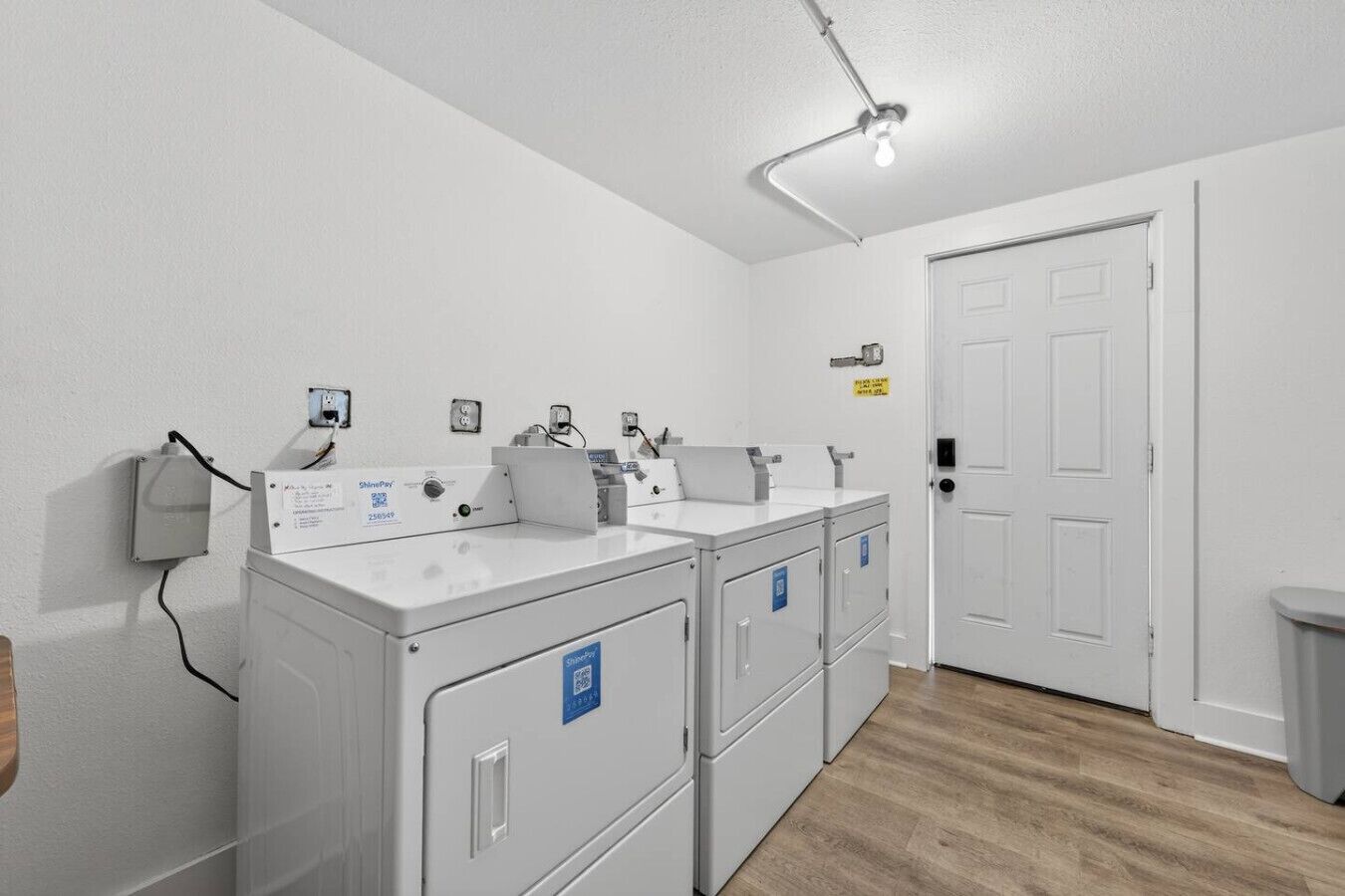 Een schone, witte badkamer met een enkele wastafel, een spiegel en een lamp.