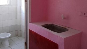 A bathroom with a pink wall, a white sink, and a white toilet. - WJV INN CORDOVA 1 (Cordova)