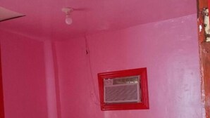 A small, pink room with a single bed, a window with a red frame, and a ceiling fan. - WJV INN CORDOVA 1 (Cordova)