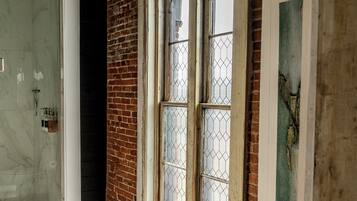 A room with a large arched window, a shower area, and a marble floor.
