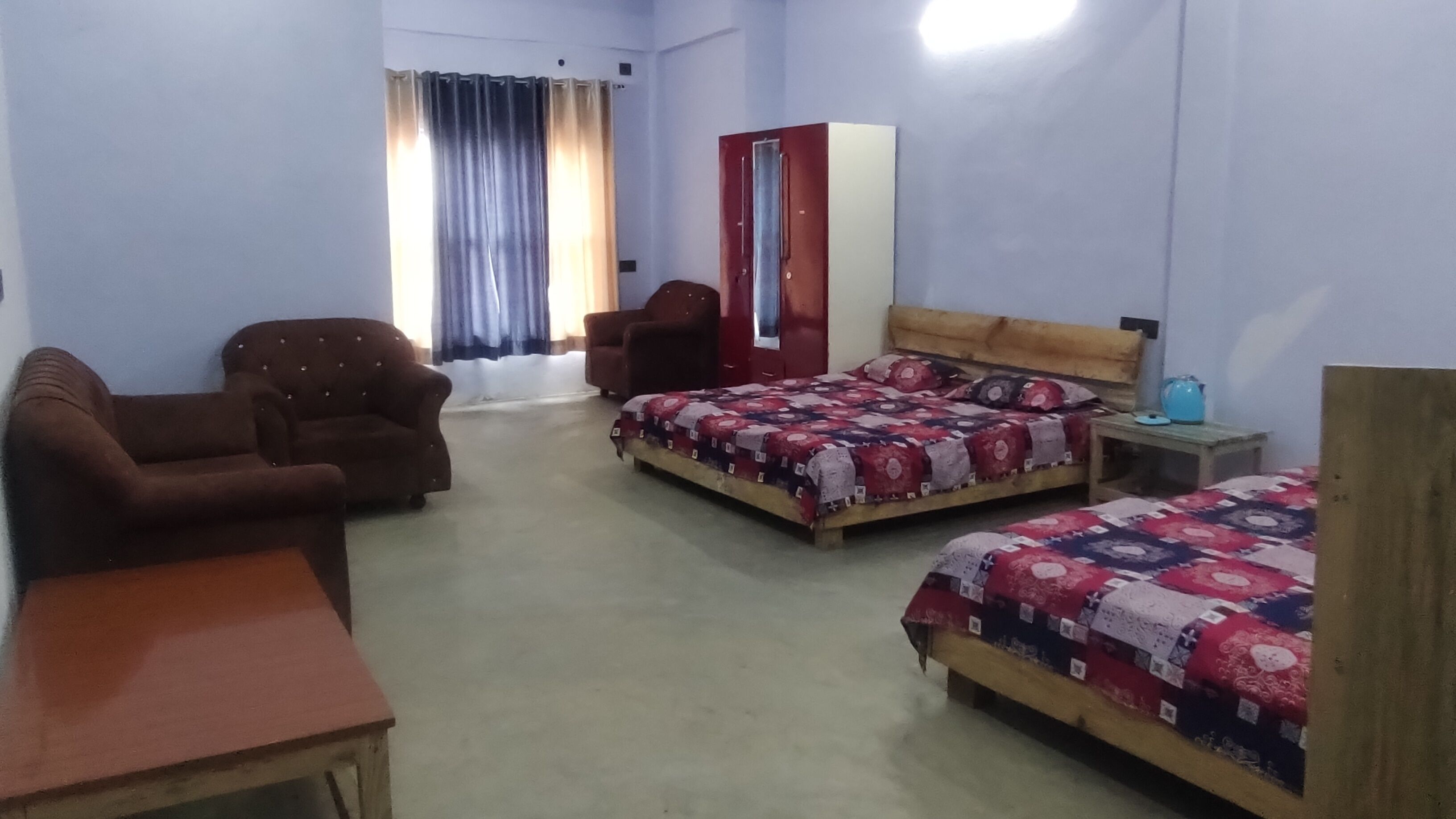 Habitación de hotel con dos camas, un sofá, un escritorio, un armario y una ventana con cortinas.