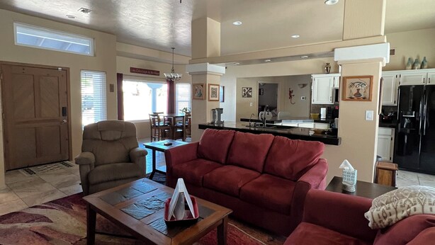 A spacious living room with a red sofa, a wooden coffee table, and a ceiling fan. - CASA LINDA - quiet, peaceful 3 bedroom home in Mesa Del Sol. (Yuma)
