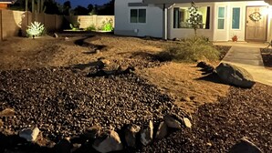 A residential area at night with a house featuring a front porch, a small garden, and a driveway. - CASA LINDA - quiet, peaceful 3 bedroom home in Mesa Del Sol. (Yuma)