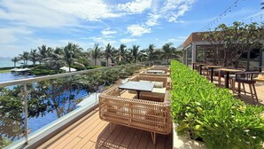 A rooftop terrace with a pool, wicker furniture, and a view of the ocean. - Luxury Villa Beach Front (Cam Lam)