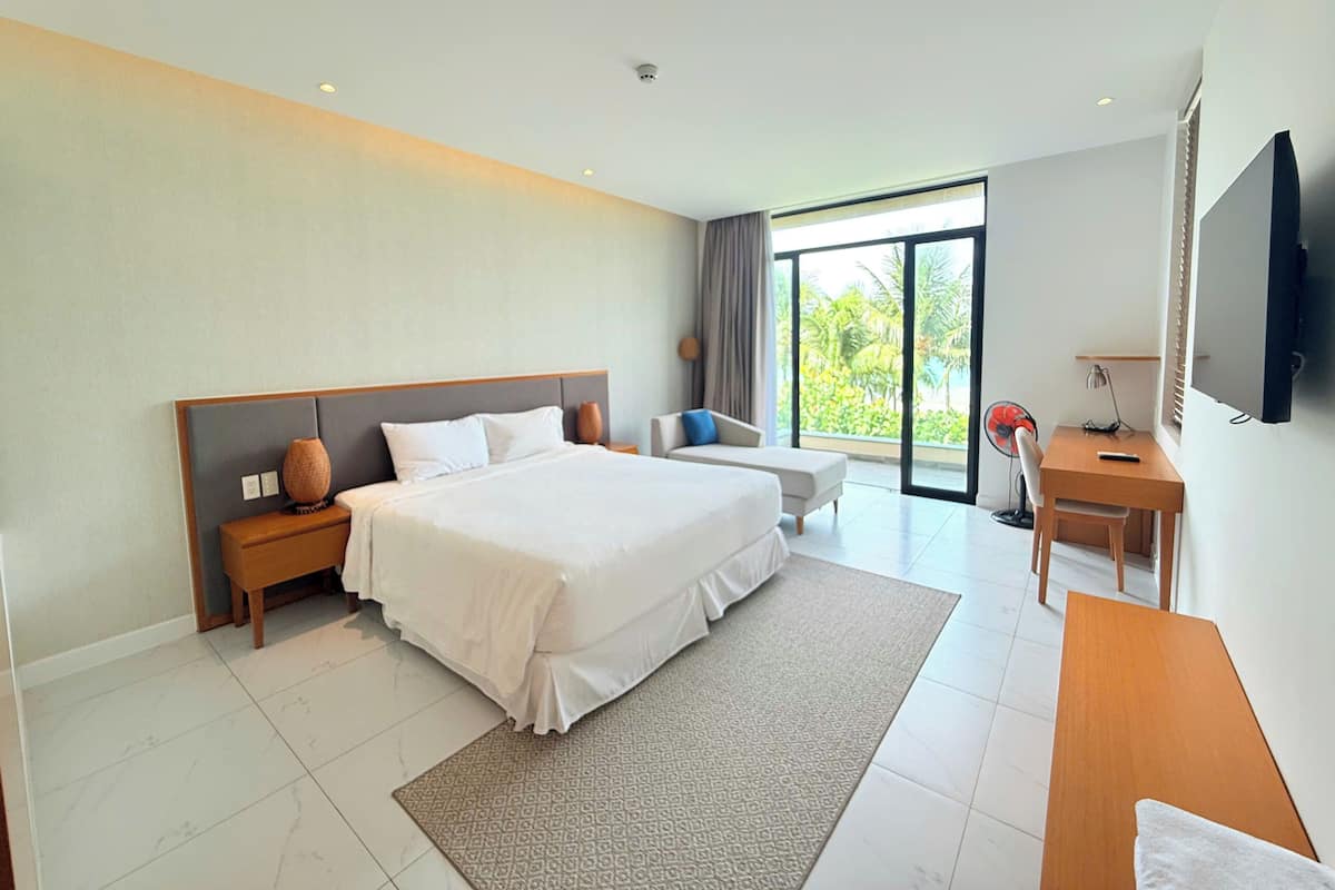 A modern hotel room with a large bed, a desk, and a TV.